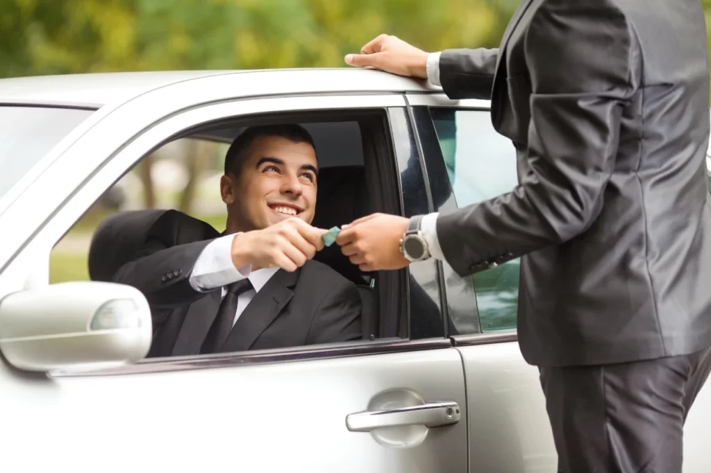 A man tipping a taxi driver in NYC by handing cash through the car window while the driver remains seated inside the cab