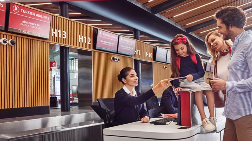 Turkish Airlines staff member warmly assists a young girl and her family at the check-in counter.
